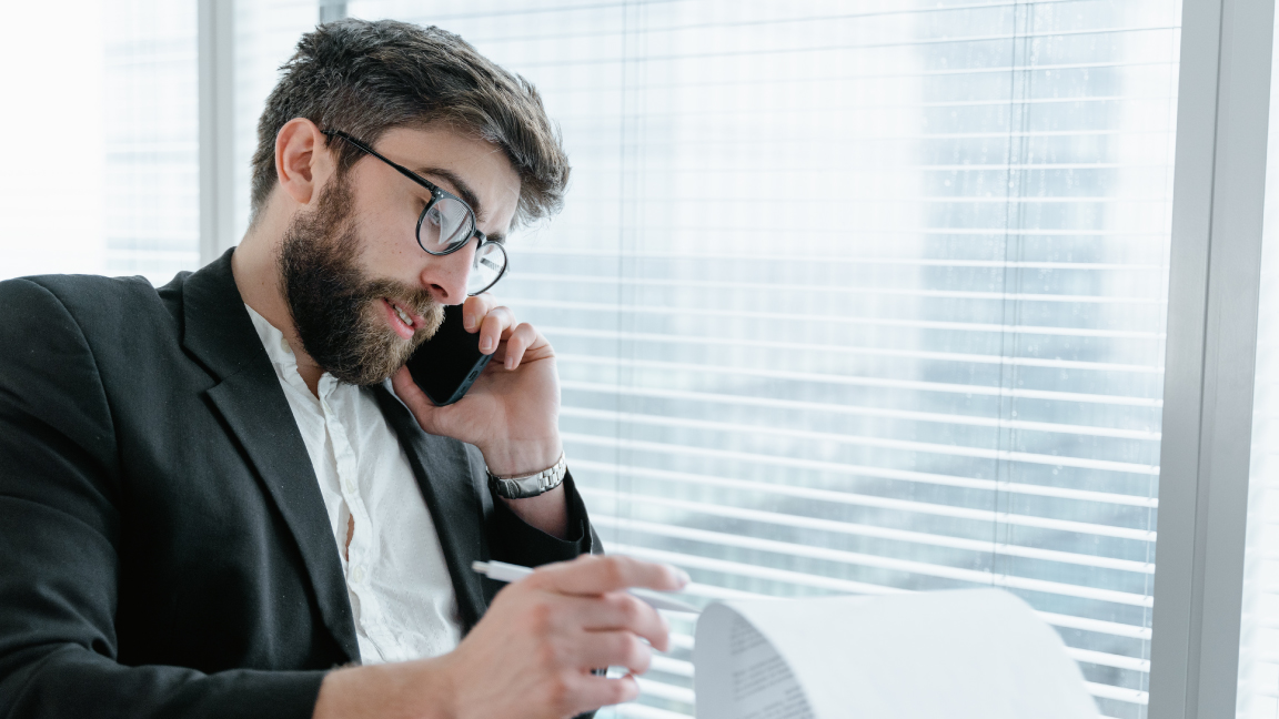 Businessman writing a note while on the phone.